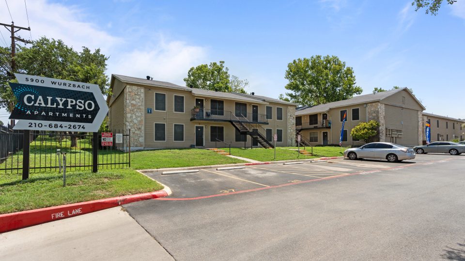 the front of the apartment complex with a parking lot at The Calypso Apartments